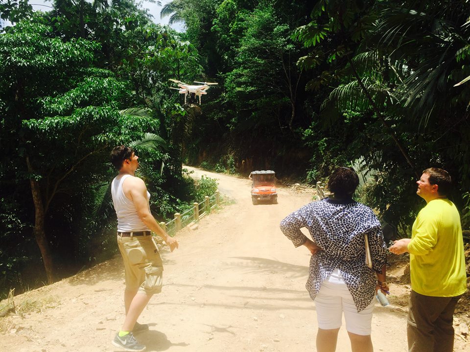 Crew launching a camera drone over the jungle road at Better in Belize with the golf cart behind