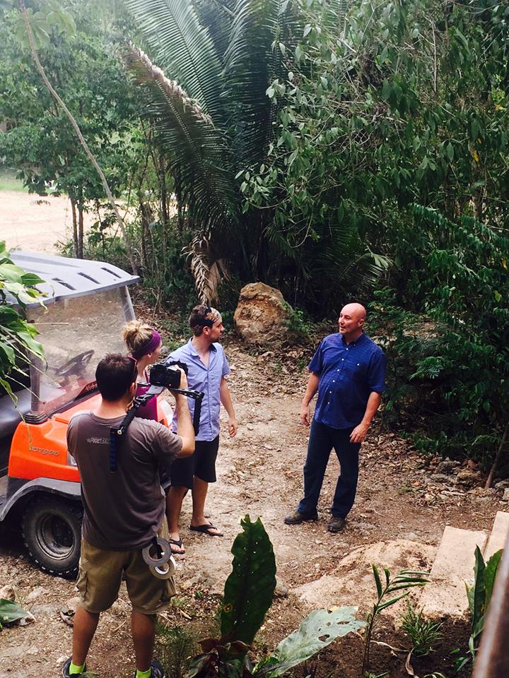 HGTV crew filming Steve with Wes and Alicia beside the golf cart on a jungle path at Better in Belize