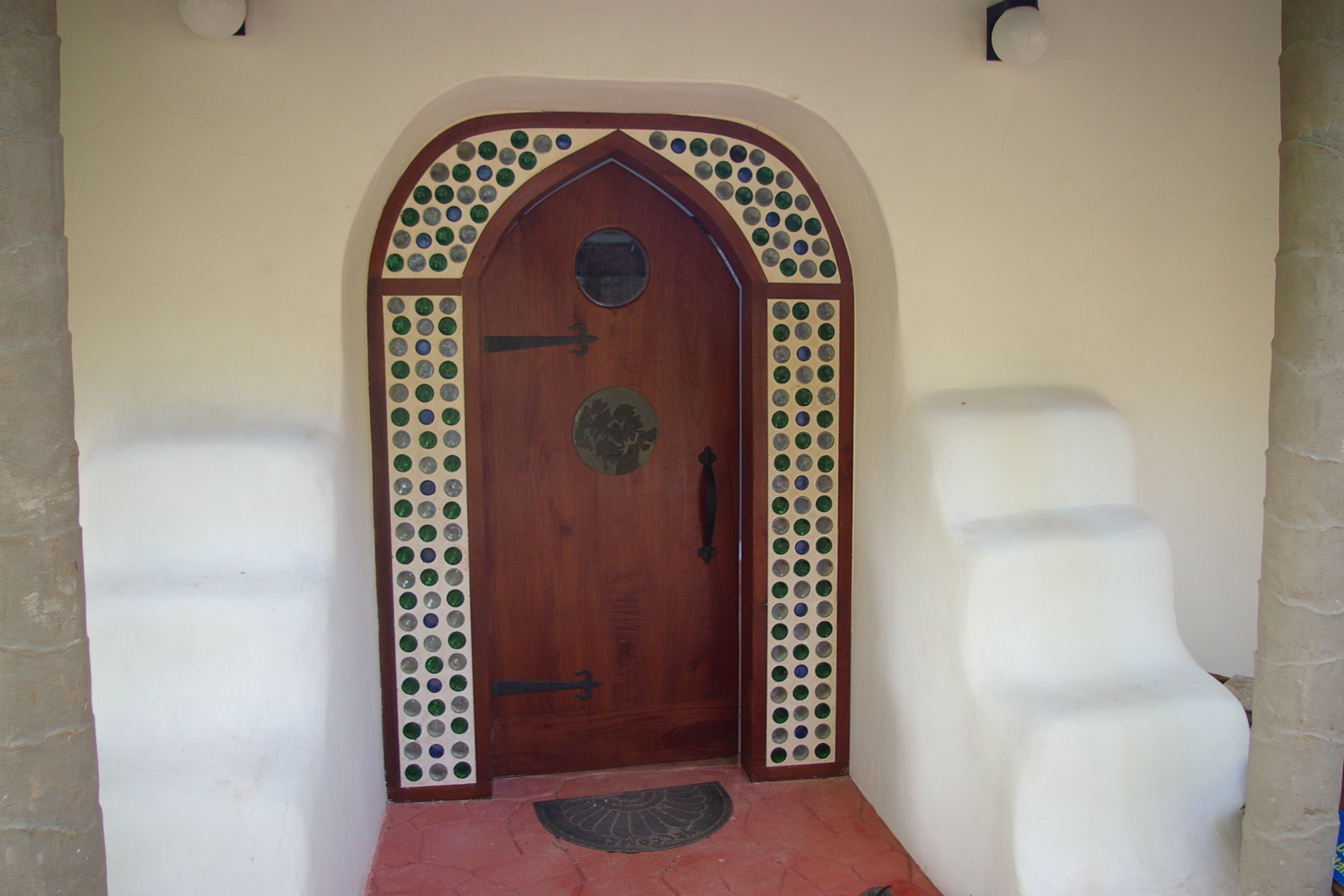 Arched wooden door framed with recycled glass bottles at the Earth Bag Home, Better in Belize