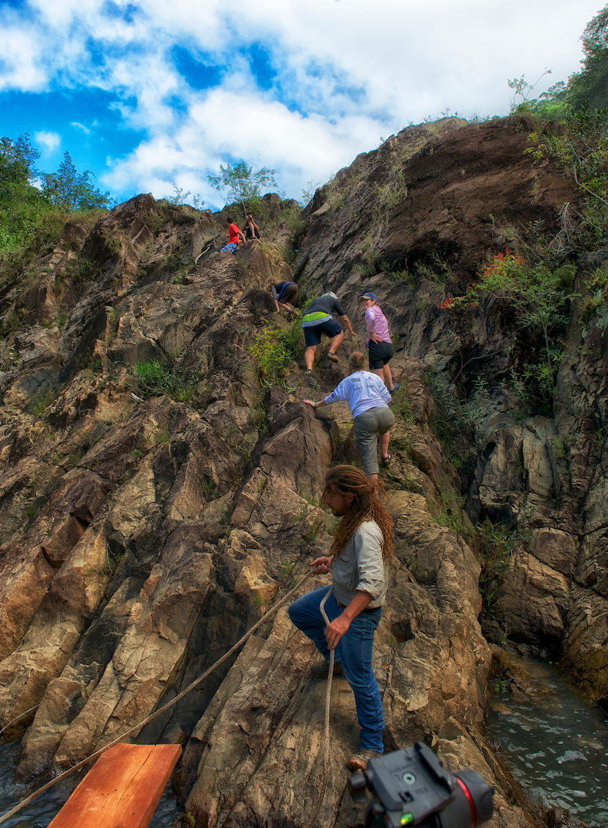 Residents and guests climbing the rocks beside a jungle river in Western Belize