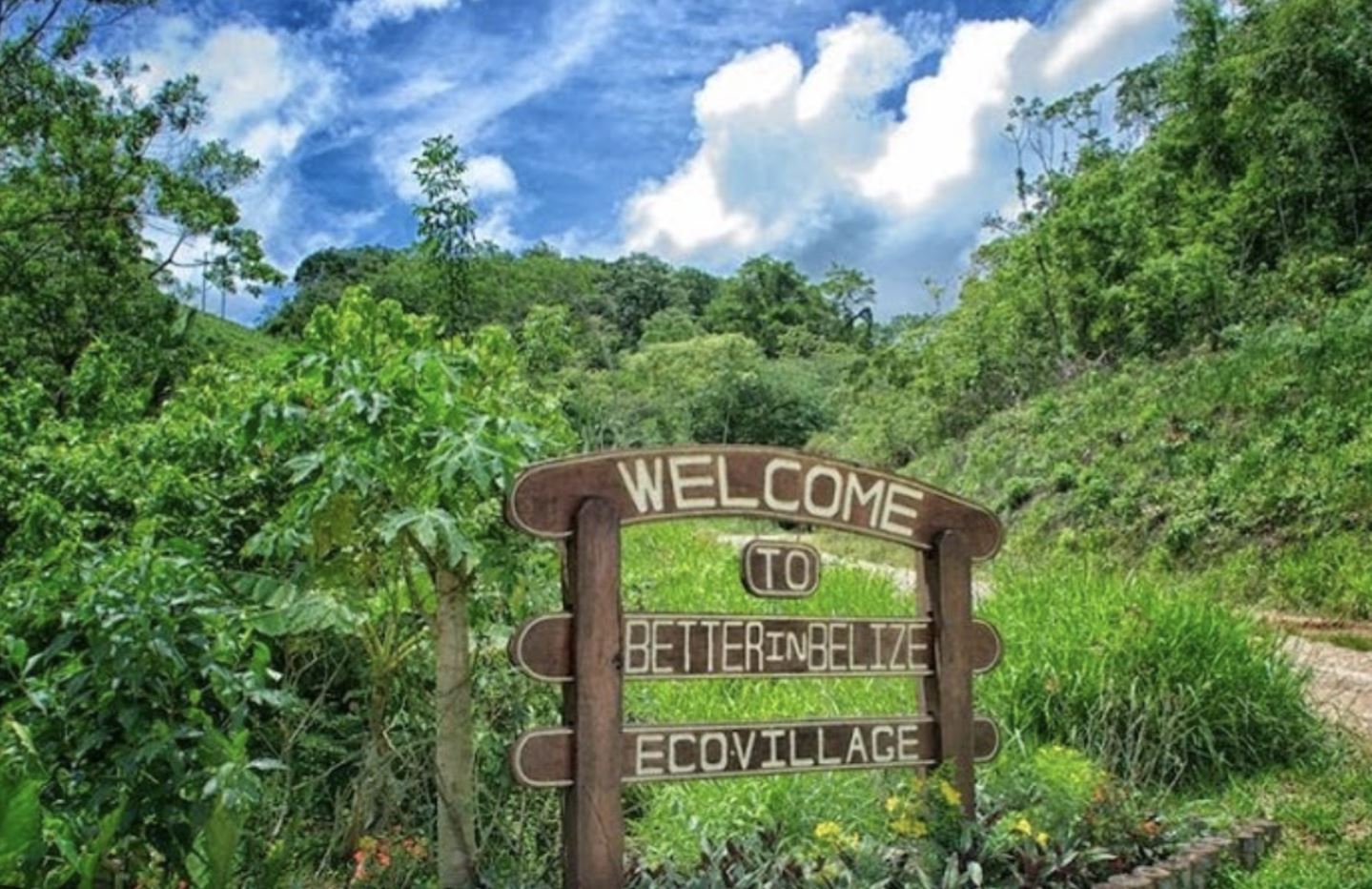 Welcome to Better in Belize Eco-Village wooden entrance sign surrounded by jungle